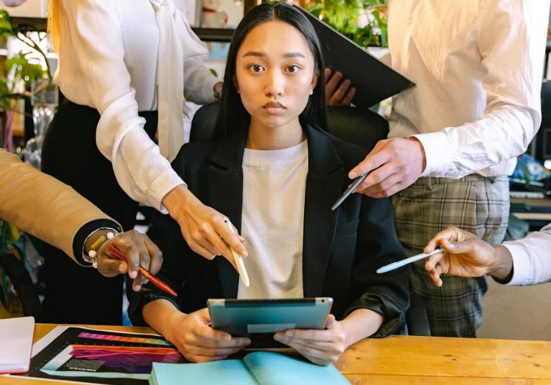 woman sitting at a desk holding a notepad surrounded with hands and pens